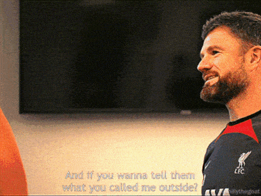 a man with a beard wearing a liverpool shirt