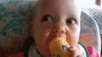 a baby is sitting in a high chair eating a yellow ice cream cone .