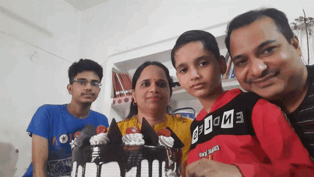 a boy wearing a shirt that says be done stands in front of a cake