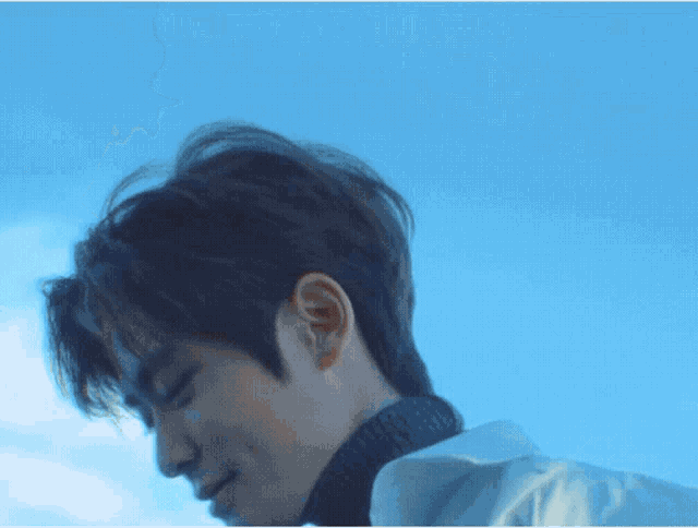 a close up of a man 's face with a blue sky behind him