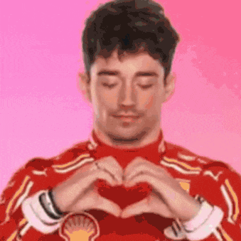 a man in a red shirt is making a heart with his hands .