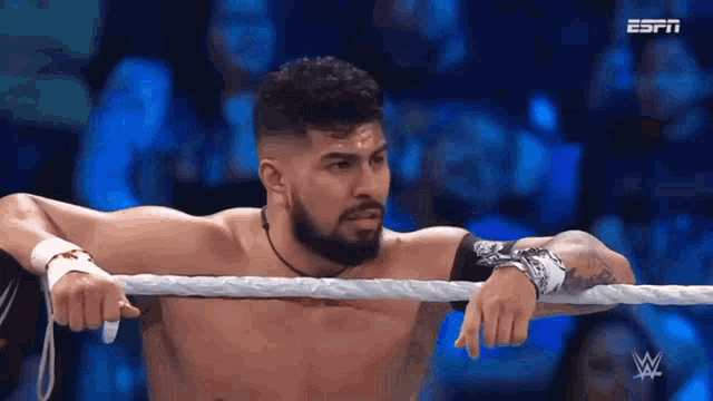 a man with a beard is leaning on a rope in a wrestling ring