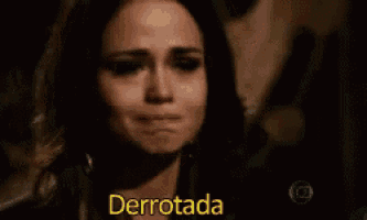 a woman is crying and the word derrotada is on the screen behind her .
