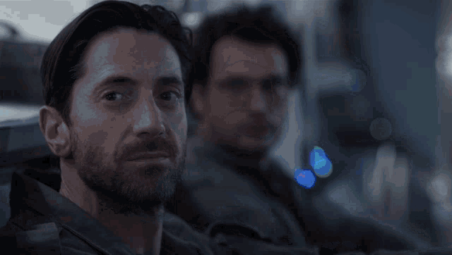 a man with a beard looks at his reflection in the mirror