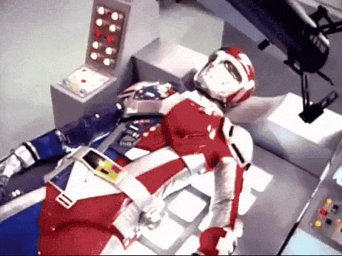 a robot in a red and white suit is laying on a table in a room .