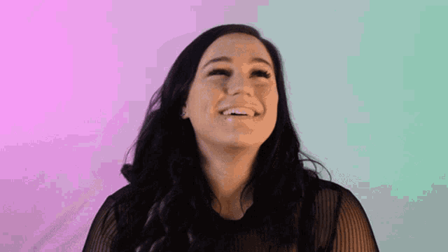 a woman in a black top is playing with her hair and smiling