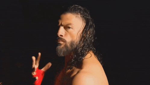 a man with long hair and a beard is standing in the dark