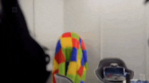 a person is sitting in a chair with a colorful blanket covering their back .