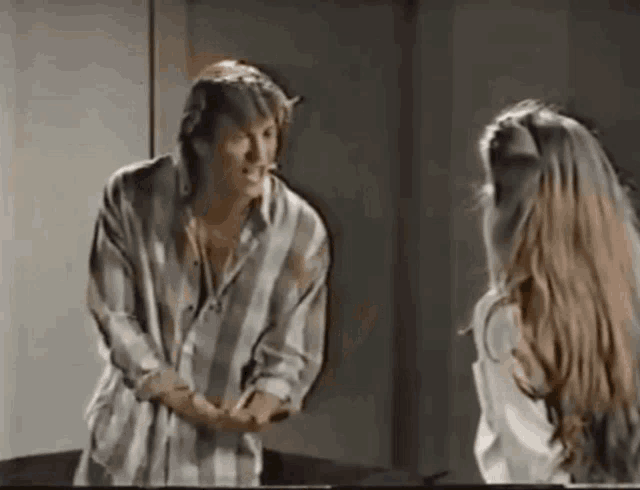a man in a plaid shirt is standing next to a woman with long hair
