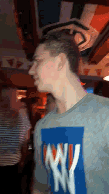 a man wearing a ny t-shirt stands in a bar