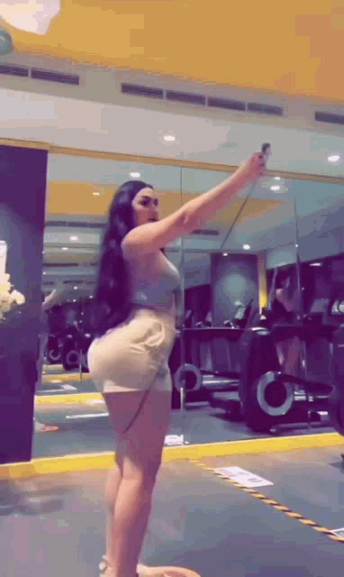 a woman is taking a picture of herself in a gym