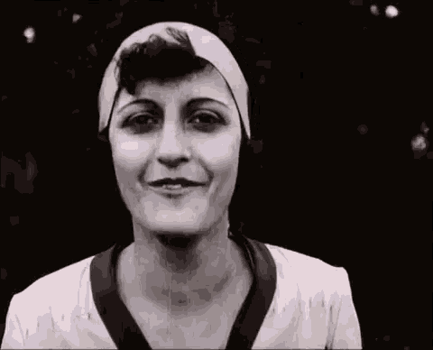 a black and white photo of a woman wearing a headband and smiling