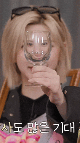 a woman is holding a wine glass in front of her face with korean writing on the bottom