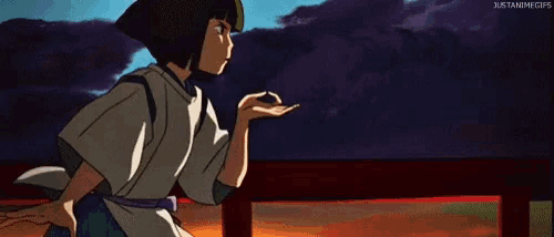 a boy in a kimono is standing on a bridge looking at petals falling .