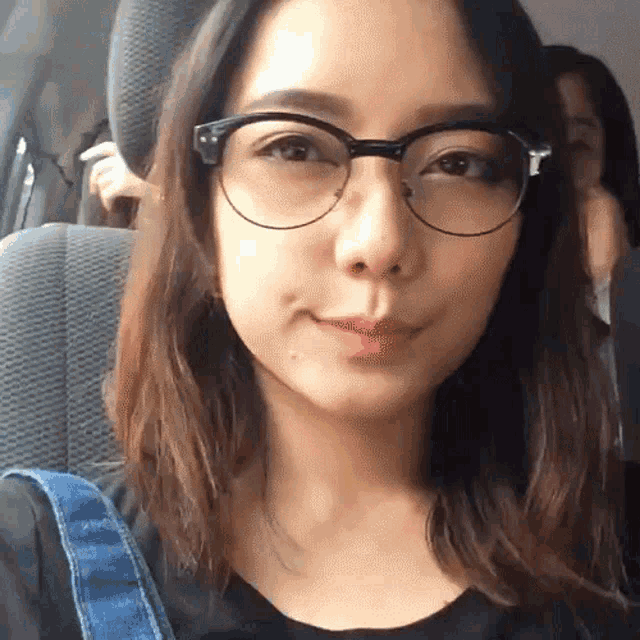 a woman wearing glasses is sitting in a car seat