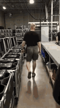 a man is walking down a hallway in a warehouse full of cases