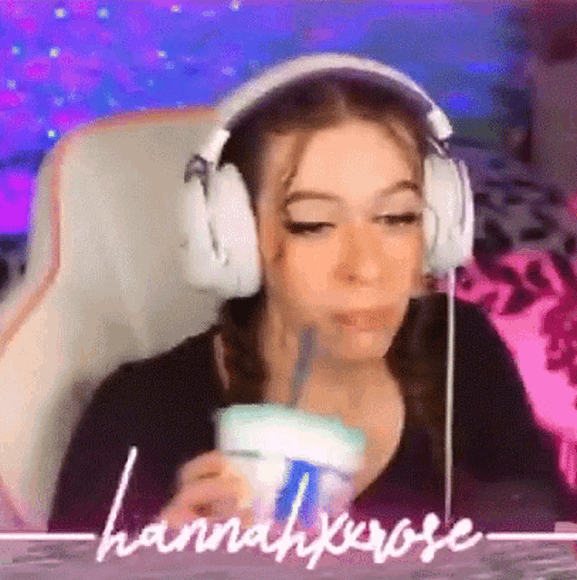 a woman wearing headphones is sitting in a chair drinking a drink .
