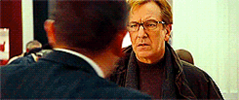 a man wearing glasses and a scarf is talking to another man .