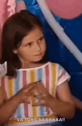 a little girl in a striped shirt is making a funny face and says la toxicaaa