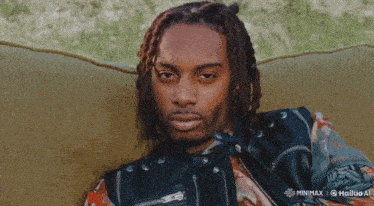 a man with dreadlocks is sitting on a couch with a minimax logo on the bottom