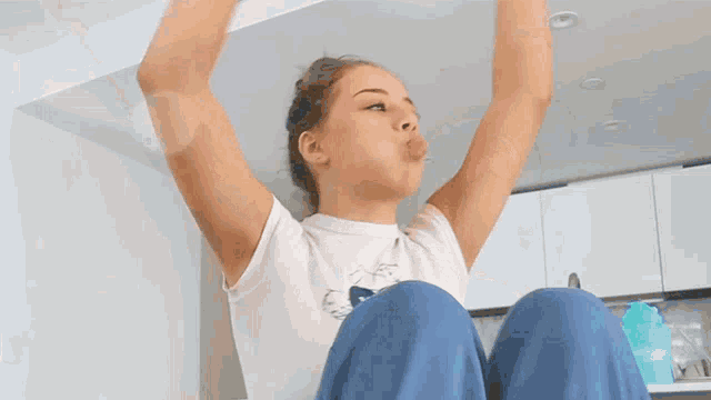a woman is sitting on the floor with her arms outstretched .
