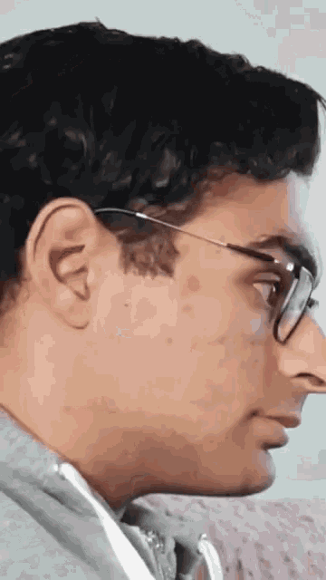 a close up of a man wearing glasses and a grey shirt