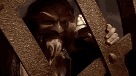 a man with a beard is behind a fence with his eyes closed .