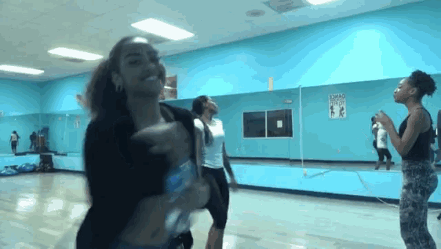 a group of women are dancing in front of a mirror in a dance studio