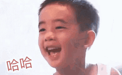 a young boy is laughing with his mouth open in front of a white wall .