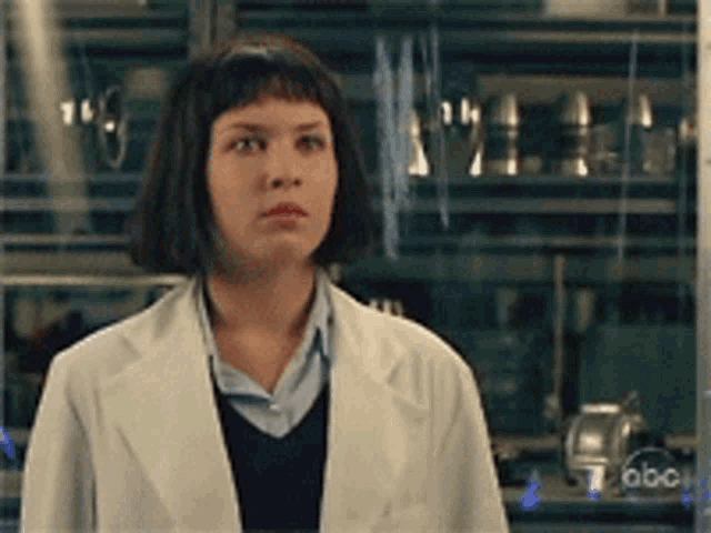 a woman in a lab coat is standing in front of a display case that says abc