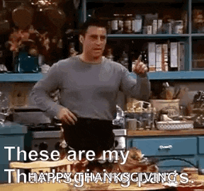 a man is standing in a kitchen with his hands on his hips and pointing .