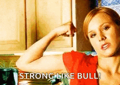 a woman in a red shirt is flexing her muscles and saying `` strong like bull '' .