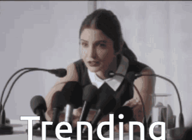a woman is giving a speech in front of microphones and the word trending is visible