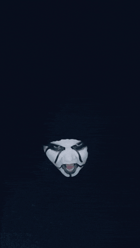 a person with a white mask on their face looks at the camera