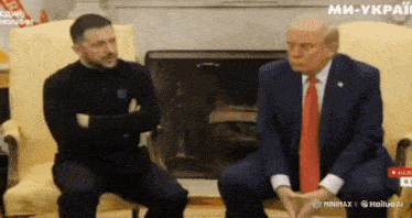 a man in a suit and tie sits next to another man