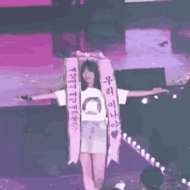 a woman is standing on a stage with her arms outstretched and holding a banner .
