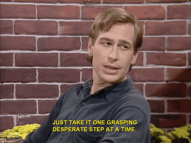 a man sitting in front of a brick wall with the words just take it one grasping desperate step at a time