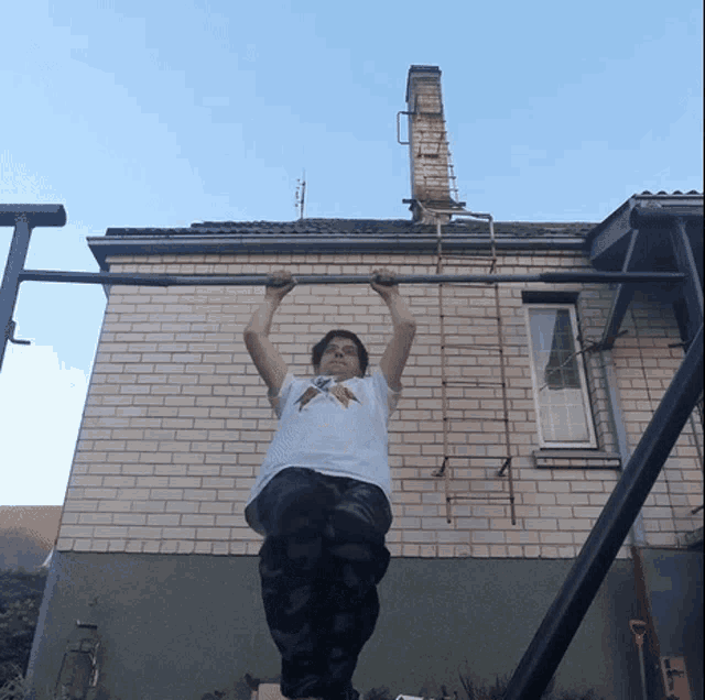 a man is doing a pull up in front of a brick house