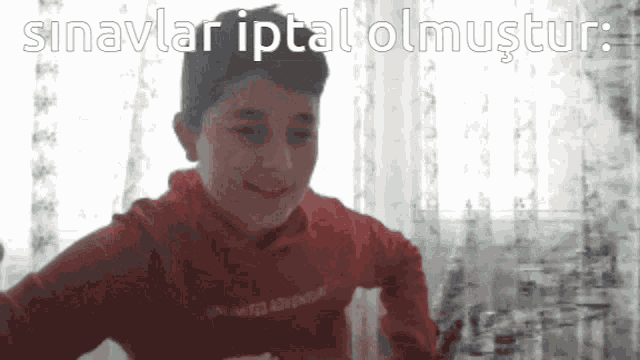 a boy wearing a red sweatshirt with the word adventure on the front