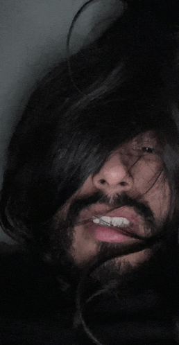 a man with long hair and a beard is smiling for the camera