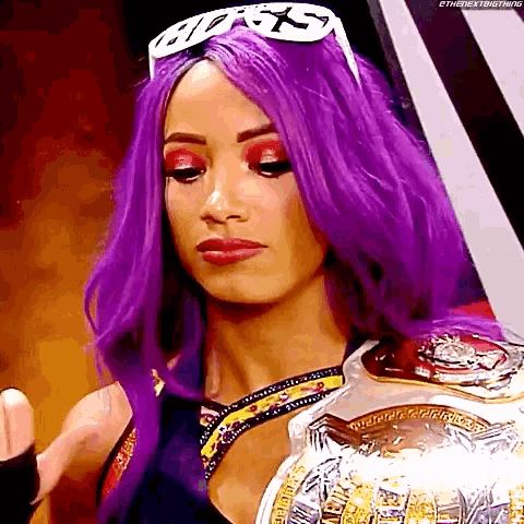a woman with purple hair is holding a championship belt