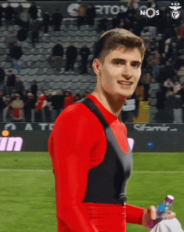 a man in a red shirt stands on a soccer field