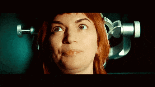 a woman with red hair looks up at something in the dark