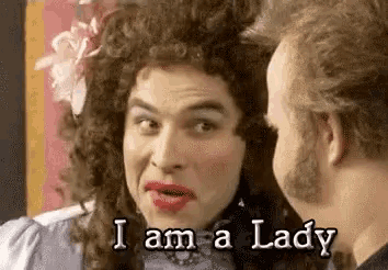 a man in a wig is talking to another man while wearing makeup .