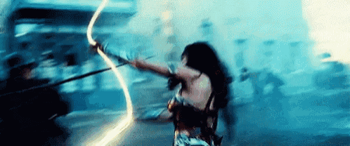 wonder woman is holding a lightning bolt in her hand while fighting a group of people .