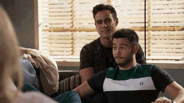 two men are sitting on a couch talking to each other