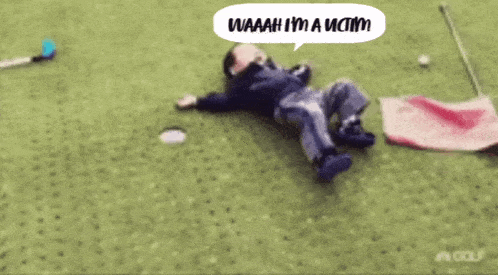 a child is laying on the grass with a speech bubble that says waaaah i 'm a victim