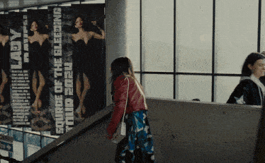 a woman walking down a set of stairs next to a poster that says your 2020 bleeding