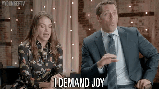 a man and a woman are sitting next to each other and the man says i demand joy