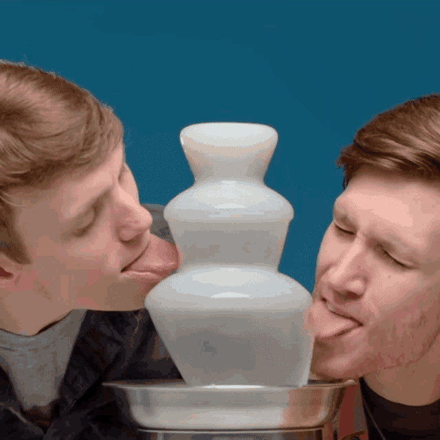 two men sticking their tongues out in front of a fountain